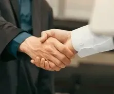 Poignée de main professionnelle et chaleureuse entre deux personnes en costume.