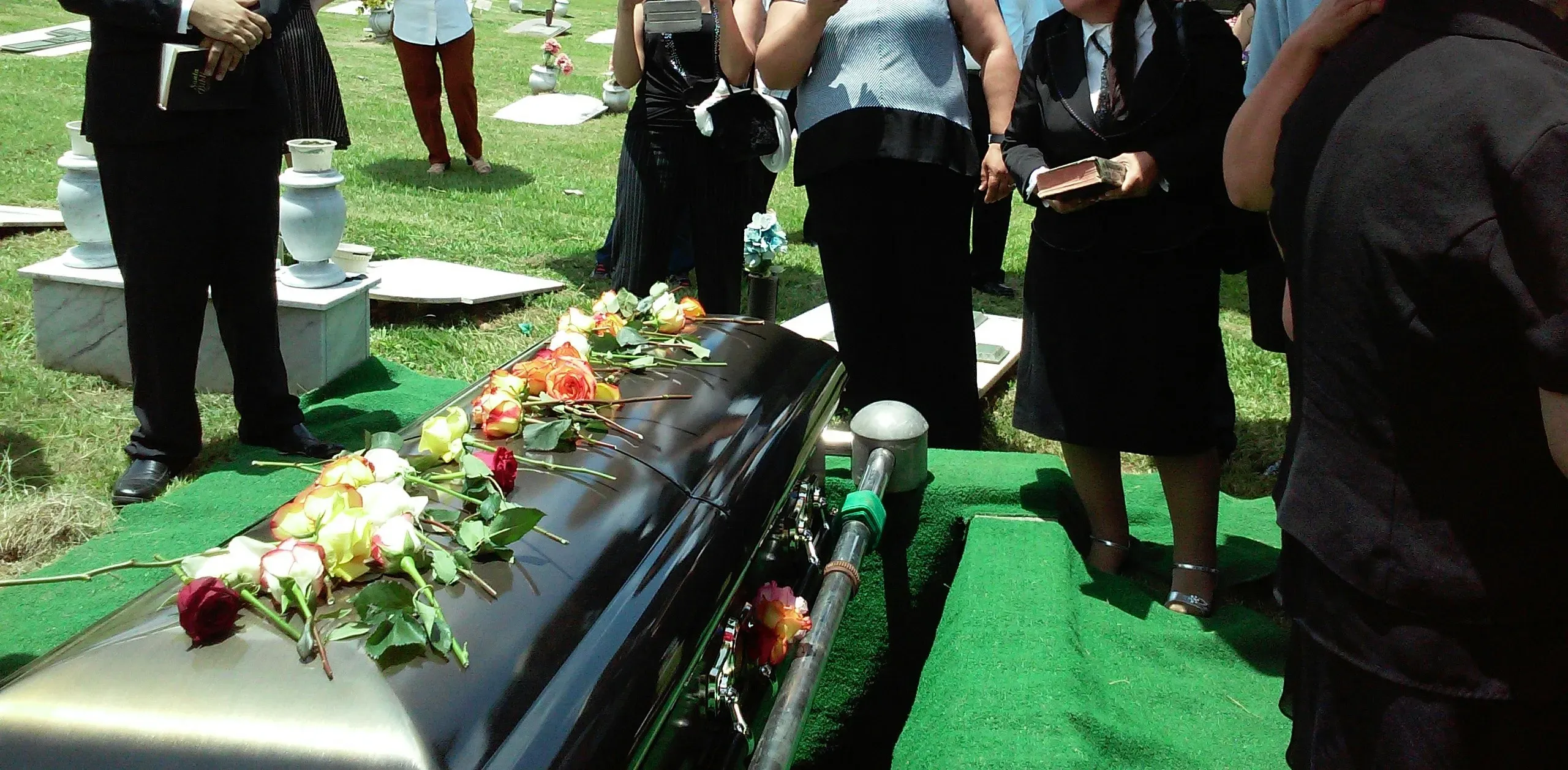 Cercueil recouvert de roses lors d'une cérémonie d'obsèques au cimetière.