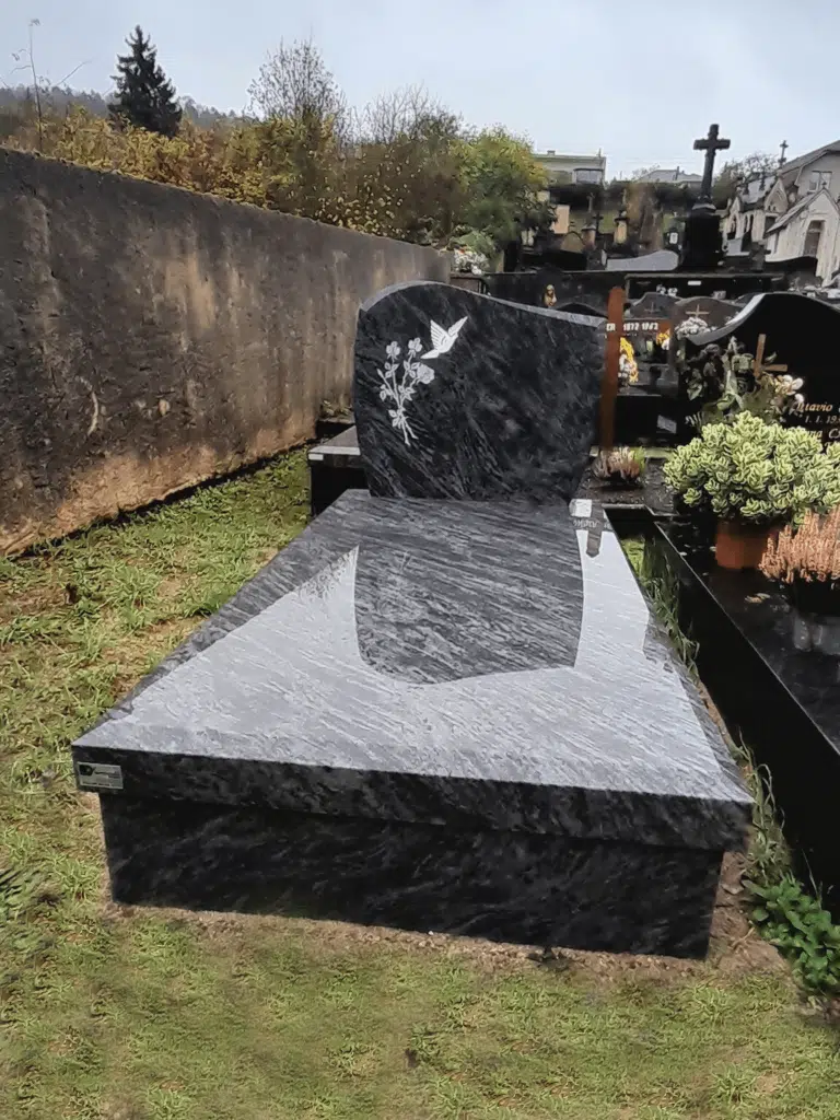 Tombe en granit veiné gris avec stèle gravée d'une colombe blanche.