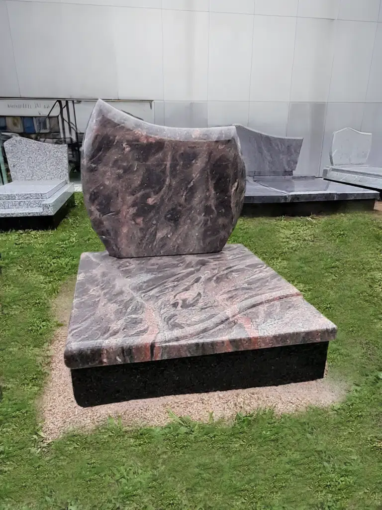 Pierre tombale cinéraire en granit rose et noir aux formes arrondies.