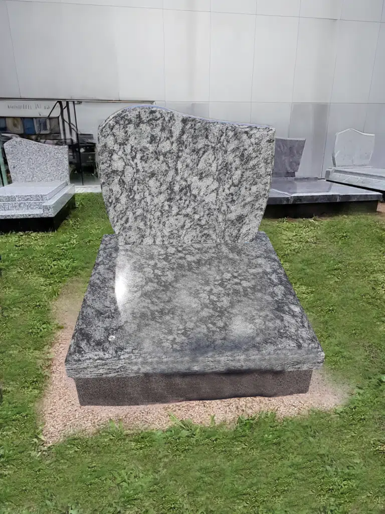 Stèle cinéraire et tombeau en granit gris moucheté sur herbe.